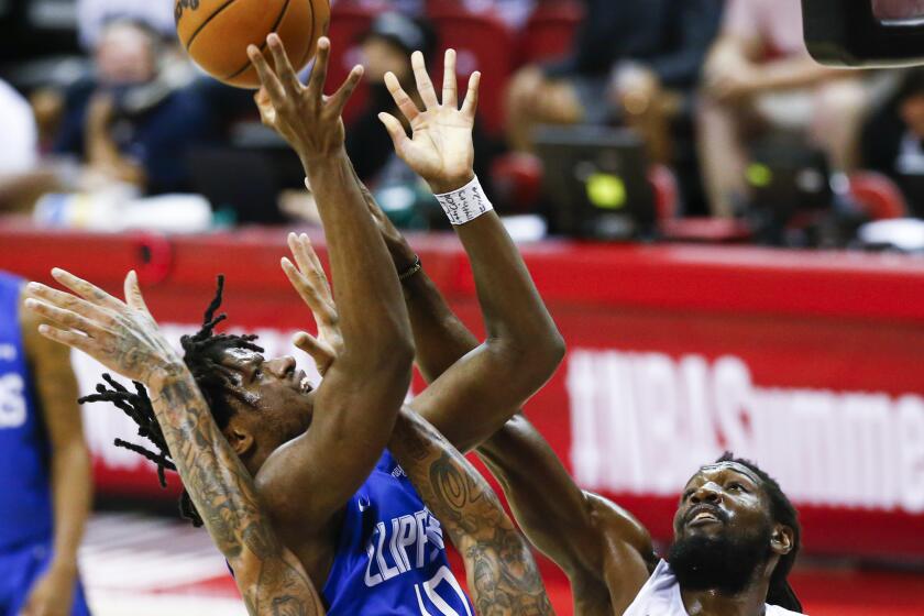 Los Angeles Clippers' Daniel Oturu shoots as Portland Trail Blazers' Michael Beasley, front, and Kenneth Faried, right