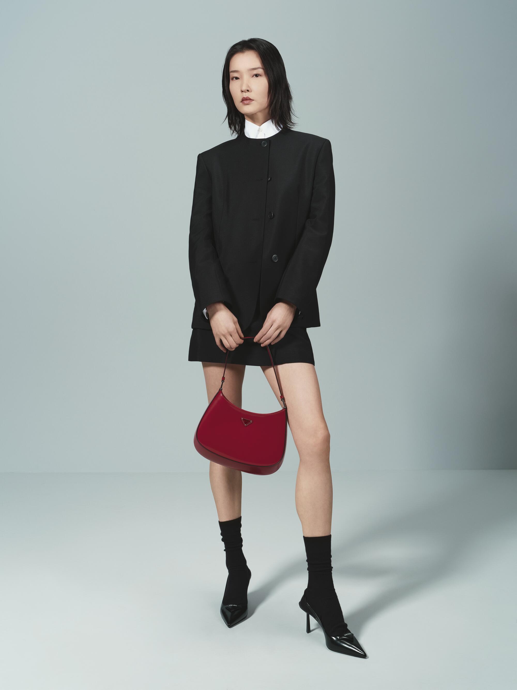 A model wears a black skirt and a jacket with a high collar