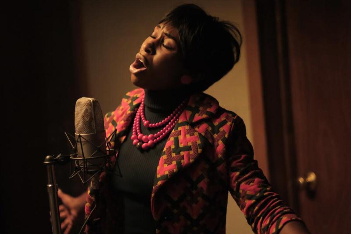 Cynthia Erivo as Aretha Franklin singing into a microphone