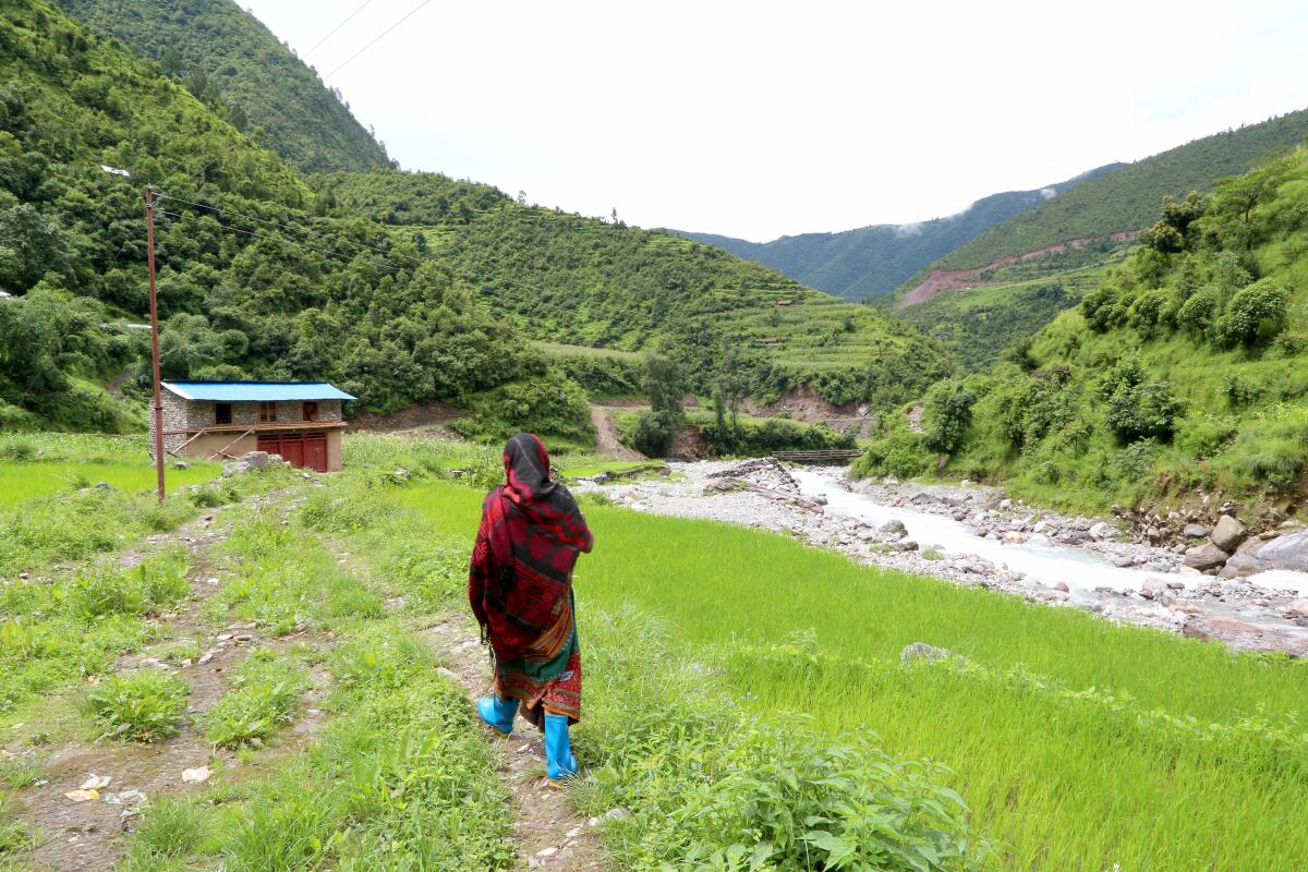 Sukbita Bhandari, now 74 years old, leads the way in blue wellies out of their village, Adhikarichaur, Nepal.