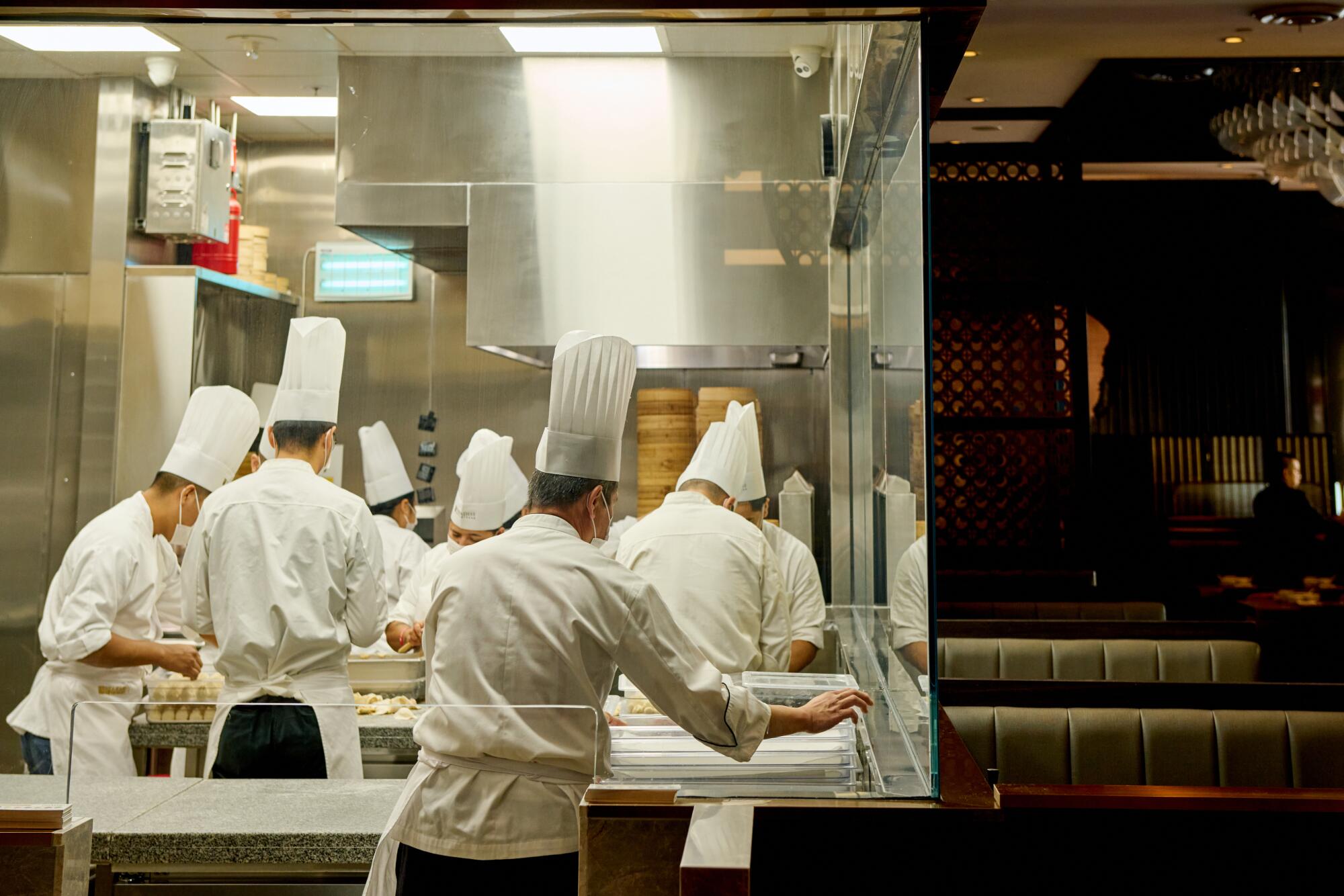 Chefs prepare dumplings, seen through a window in Paradise Dynasty's dining room. 