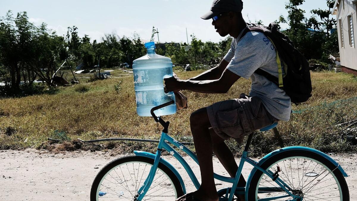A man rides a bike with a container of water on Barbuda on Dec. 8. Many homes on the island still lack water service following Hurriance Irma.
