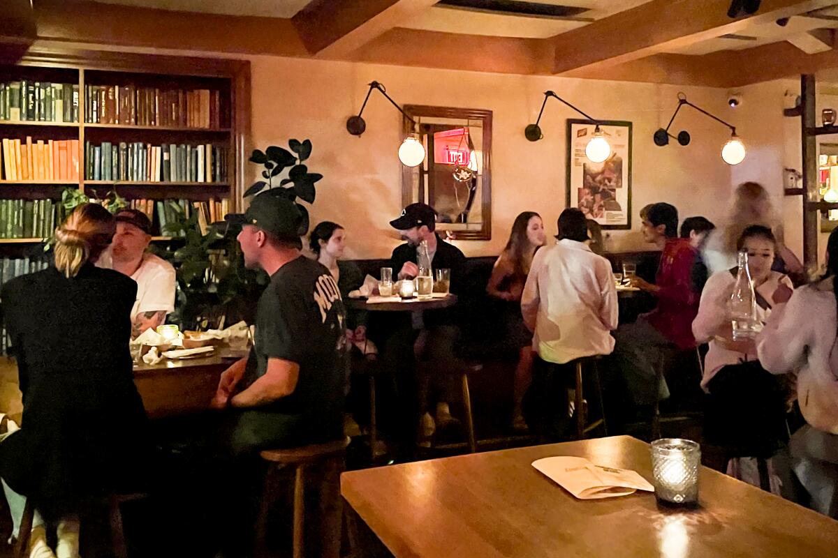 Lowboy, with groups of people sitting at bar tables and shelves full of books.