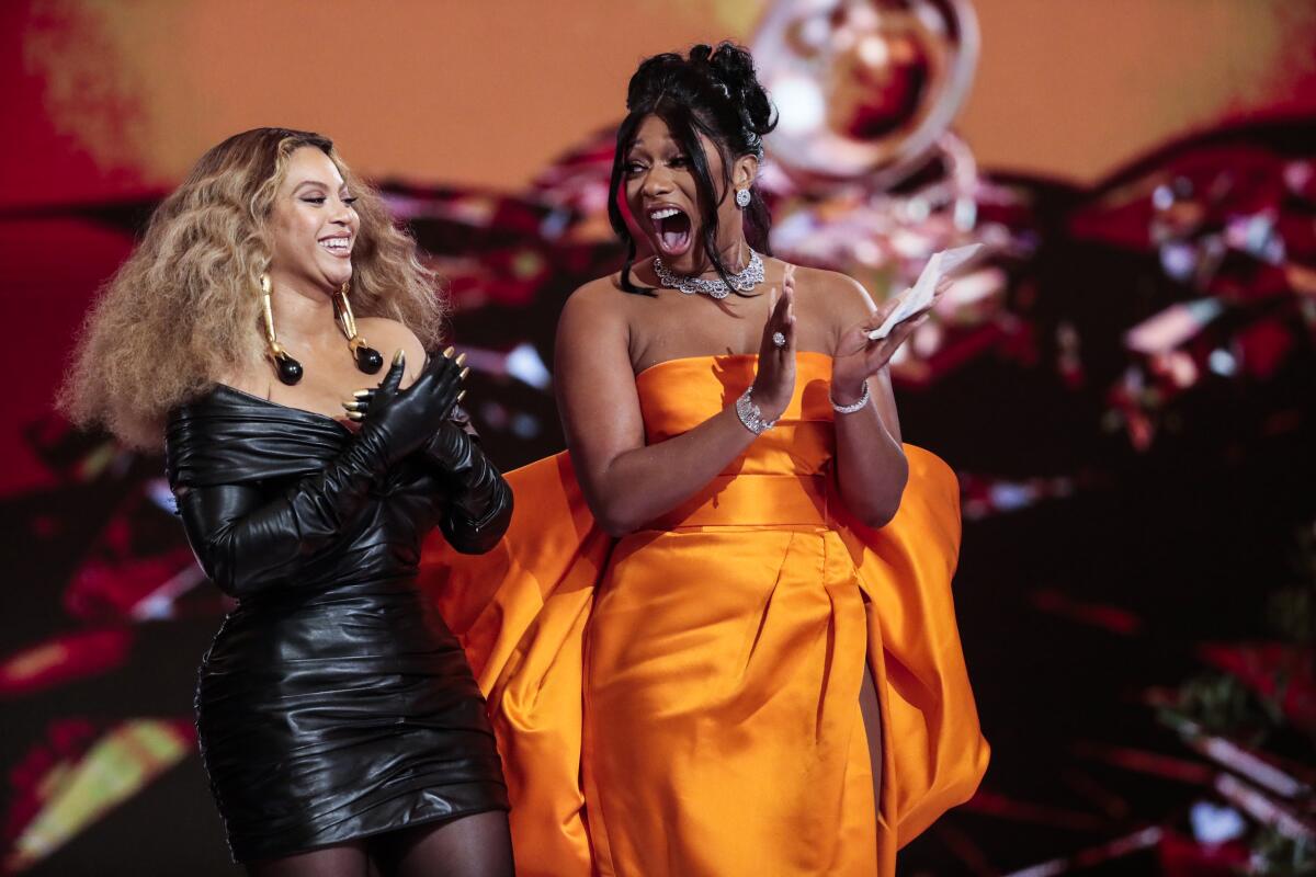 Beyoncé in a black dress and gloves and Megan Thee Stallion in an orange gown.