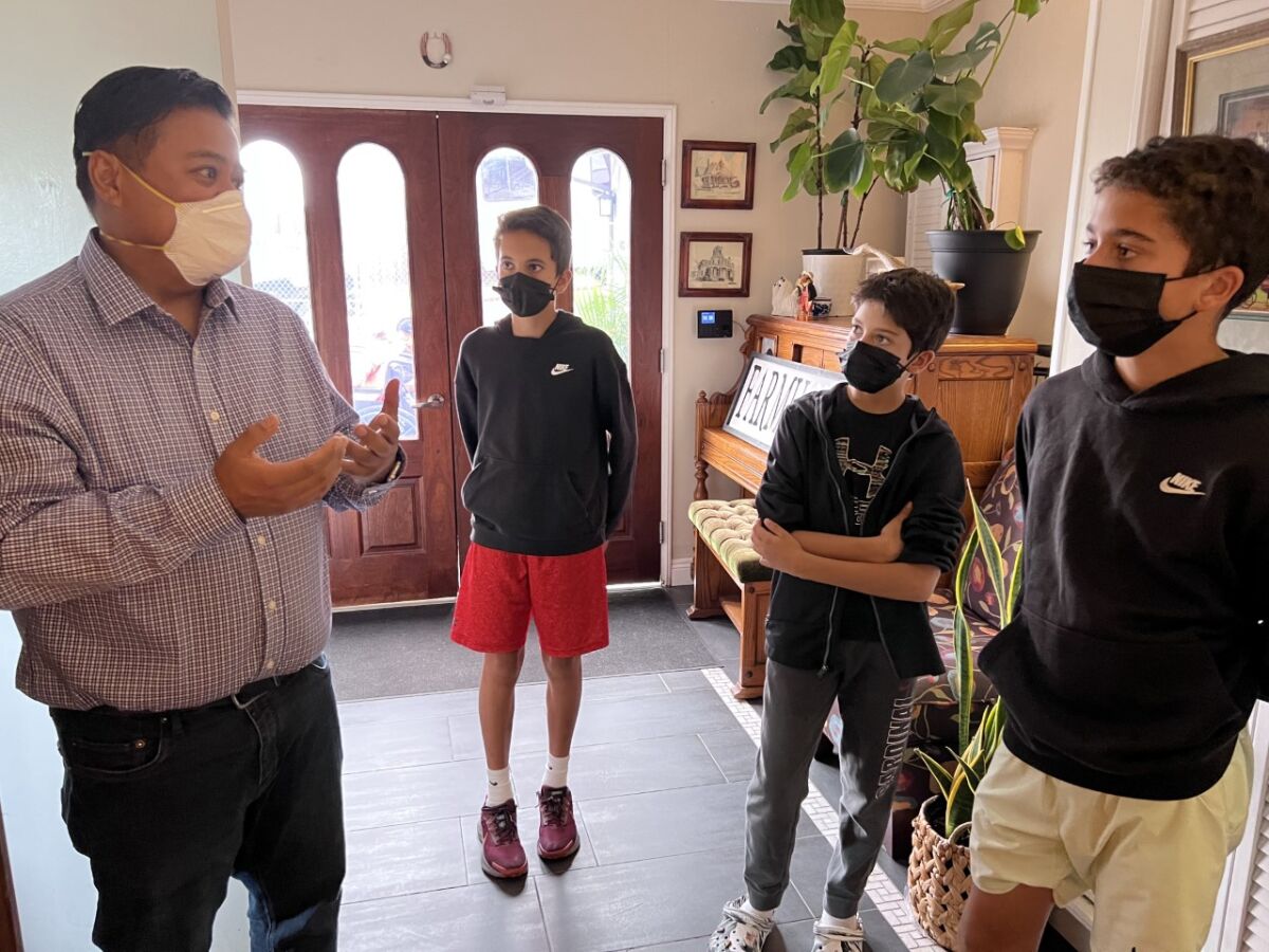 a man and three boys stand in a hallway wearing face masks