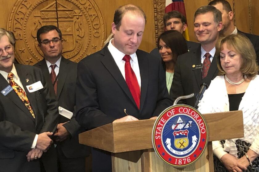 Colorado Gov. Jared Polis, at podium, signs into law Senate Bill 19-181 at the State Capitol in Denver, Colo., Tuesday, April 16, 2019. Gov. Polis signed into law a major overhaul of state oil and gas rules, shifting the focus away from encouraging production and directing regulators to make public safety and the environment their top priority. (AP Photo/Dan Elliott)