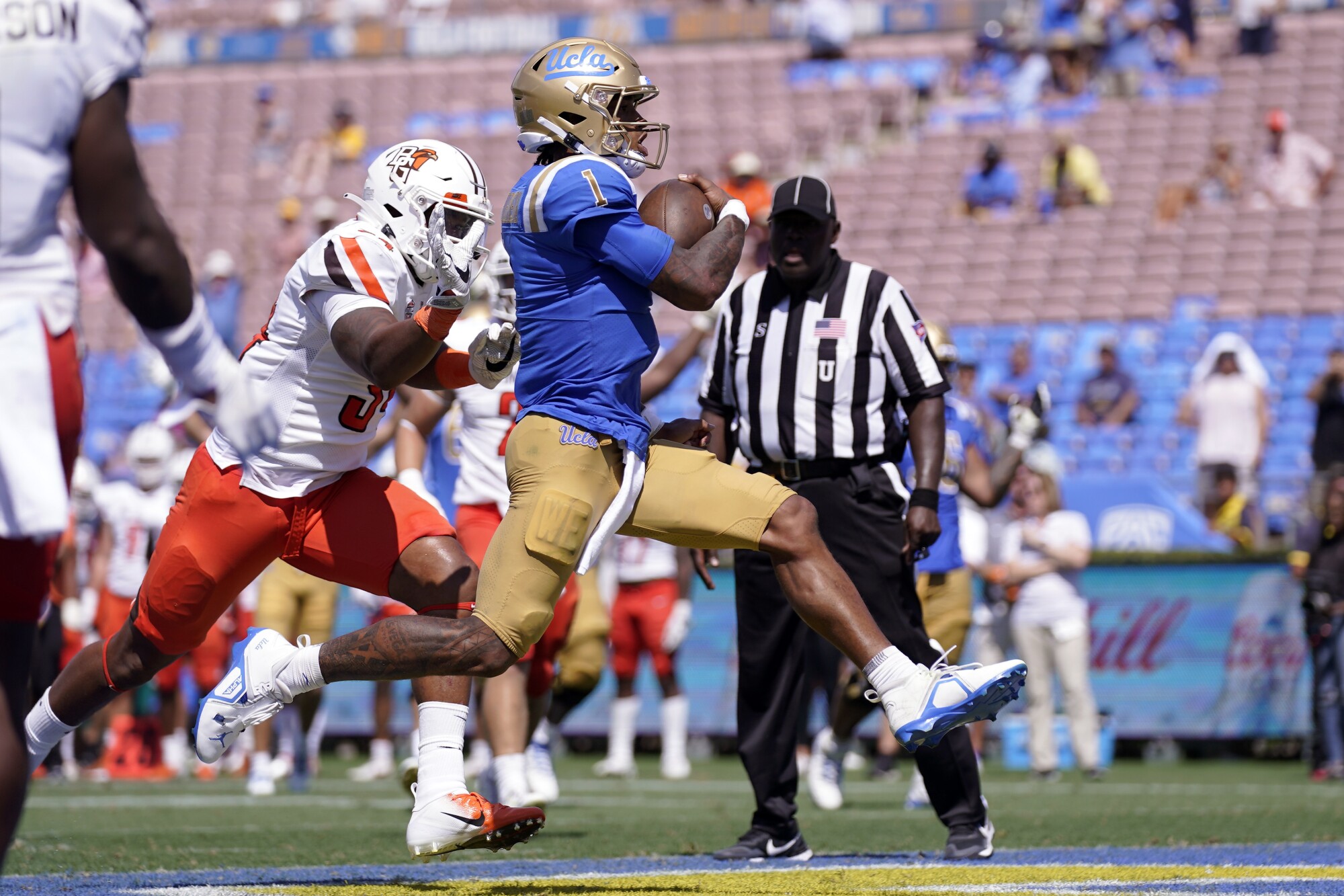 Le quart-arrière de l'UCLA Dorian Thompson-Robinson passe devant le joueur de ligne défensive de Bowling Green Adrian Wilson.