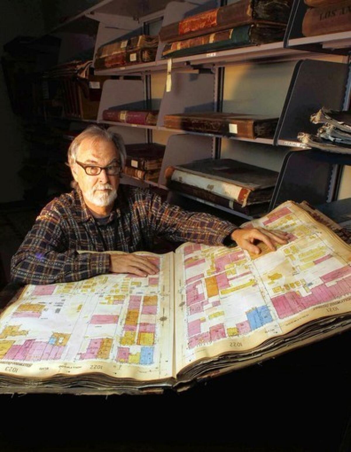 Glen Creason, map librarian at the Los Angeles Central Library, pulls out one of the large, heavy volumes of Sanborn maps — detailed drawings of each block of the city prepared for insurance purposes that are troves of information about old Los Angeles.