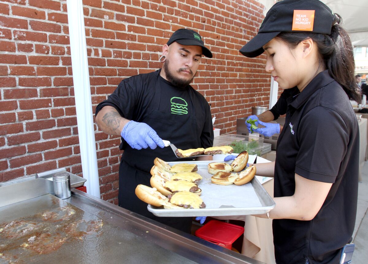 Shake Shack pro griller Mike Cosenza, left, and West Hollywood store manager Debbie Gan prepare sample burgers at an event announcing five new restaurants opening soon at Brand and Colorado in Glendale on Thursday, May 12, 2016.