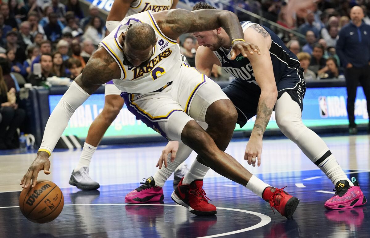 Lakers forward LeBron James reaches down toward the court for a loose ball.