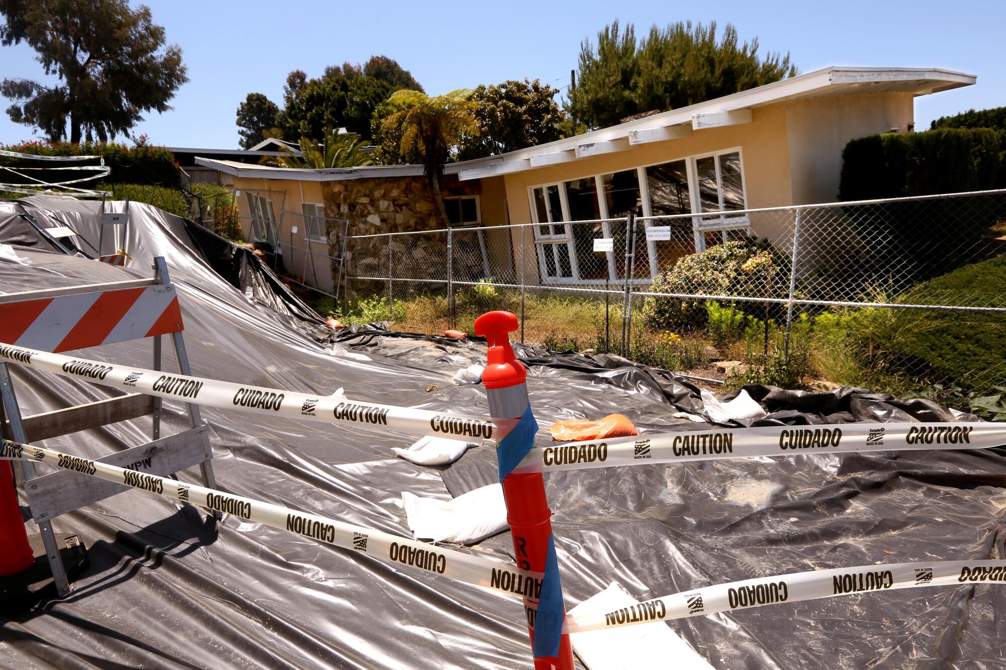 A house, badly slumped by land movement, is blocked by caution tape.