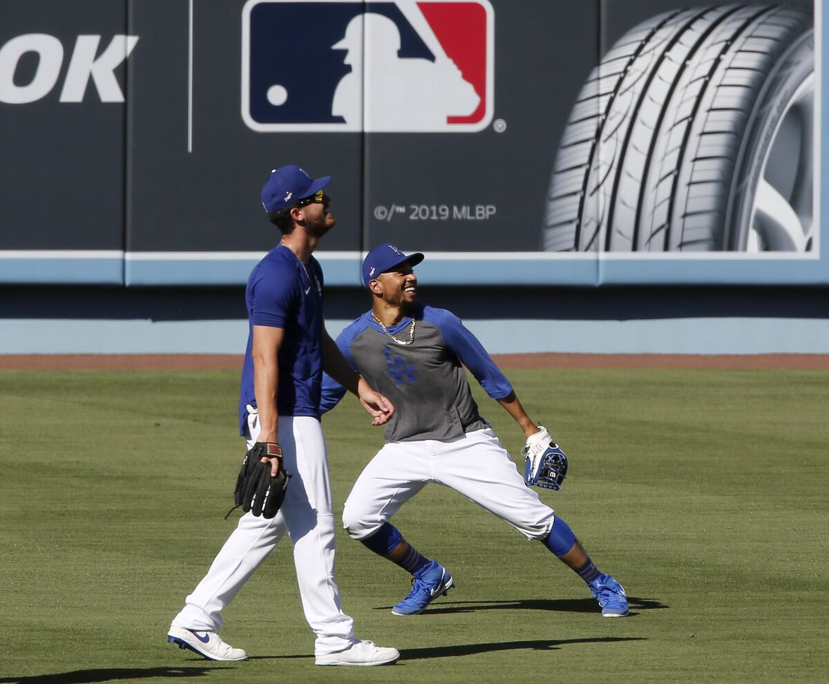Dodgers right fielders Cody Bellinger, left, and Mookie Betts catch fly balls during practice at Dodger Stadium on Friday.