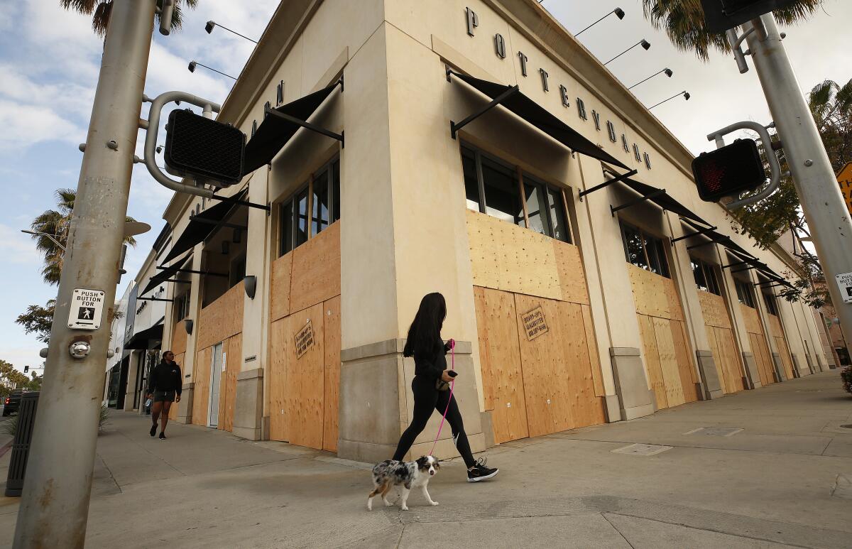 Victoria Perry walks her dog Cleo past a boarded-up Pottery Barn on April 2 in Beverly Hills.