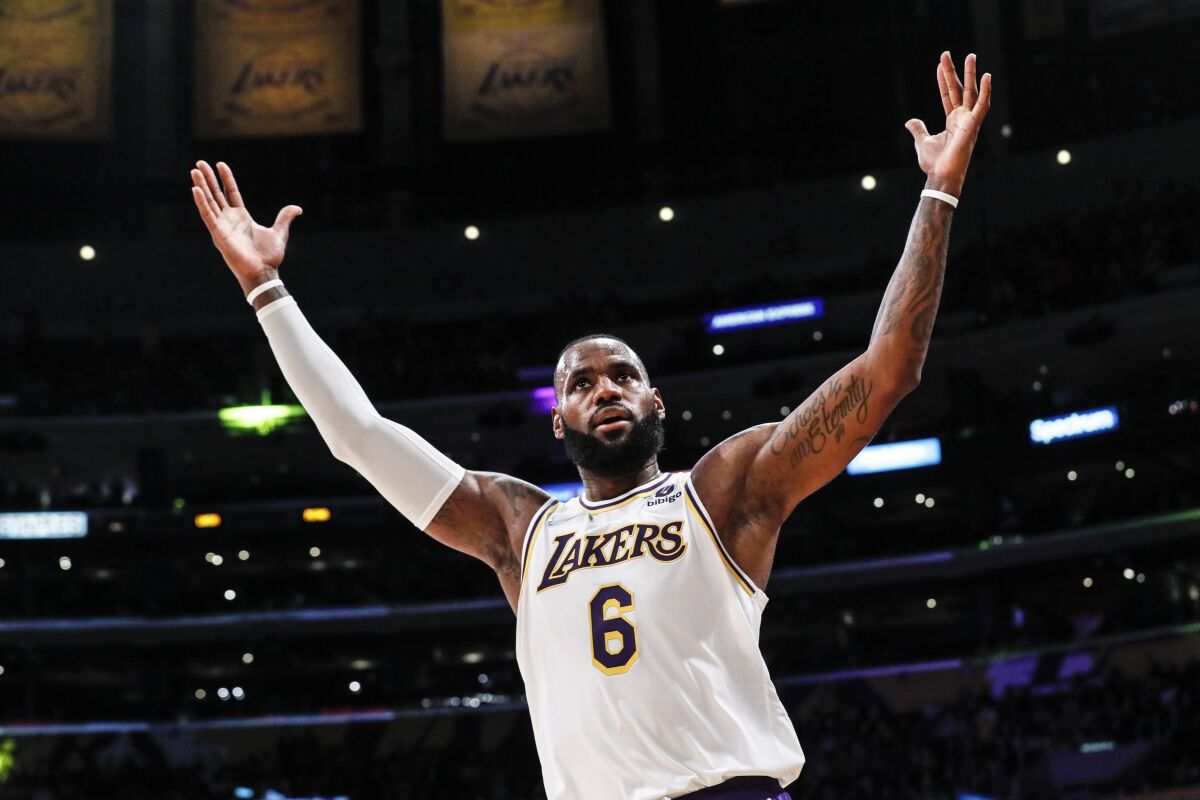 Lakers forward LeBron James raises his arms in celebration during a game.