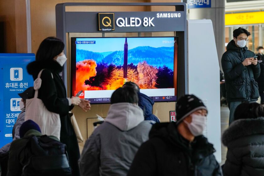 People at a railway station in Seoul watch a TV showing the launch of a North Korean missile.