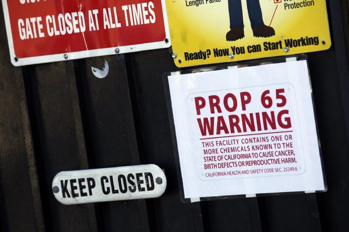 A Prop. 65 Warning is posted on a gate at Aerocraft Heat Treating in Paramount