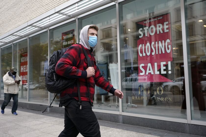 A passer-by walks past a store closing sign, right, in the window of a department store in Boston on Tuesday.