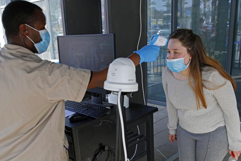 A security guard double checks a customer after she was screened by a body temperature screening device, before entering an IKEA outlet in the Israeli coastal town of Netanya on April 22, 2020, after authorities eased down some of the measures that have been in place during the novel conronavirus pandemic crisis. (Photo by JACK GUEZ / AFP) (Photo by JACK GUEZ/AFP via Getty Images)