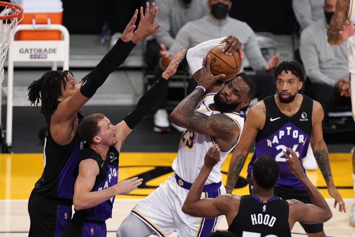 Lakers forward LeBron James is surrounded by Raptors defenders while trying to score on a layup.