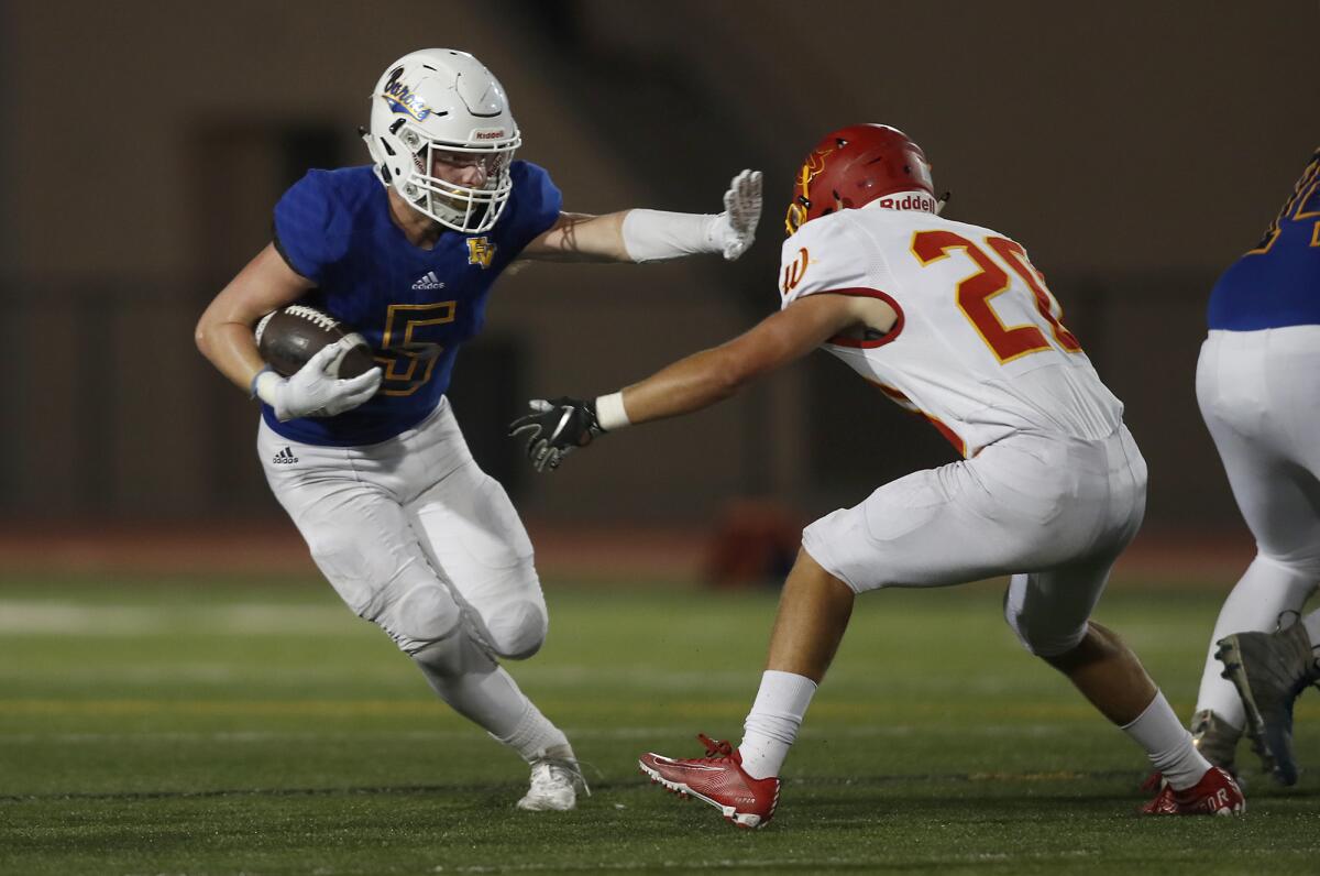 Fountain Valley running back Tanner Ciok (5) stiff-arms Woodbridge's Owen Lucas in the first half of a nonleague game on Thursday at Huntington Beach High.