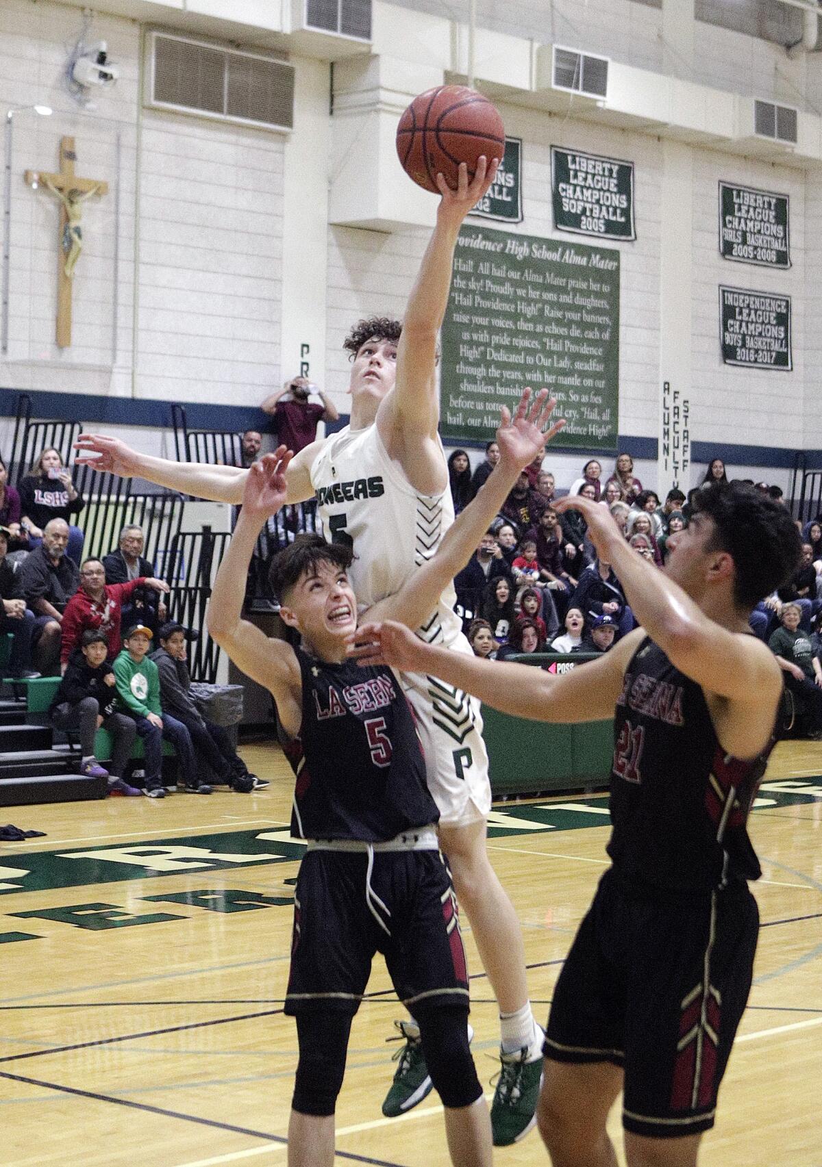 Providence's Collin Ferrell reaches for a rebound over La Serna's Ruben Nunez in the CIF Southern Section Division III-AA quarterfinal boys' basketball playoff at Providence High School on Tuesday, February 18, 2020.