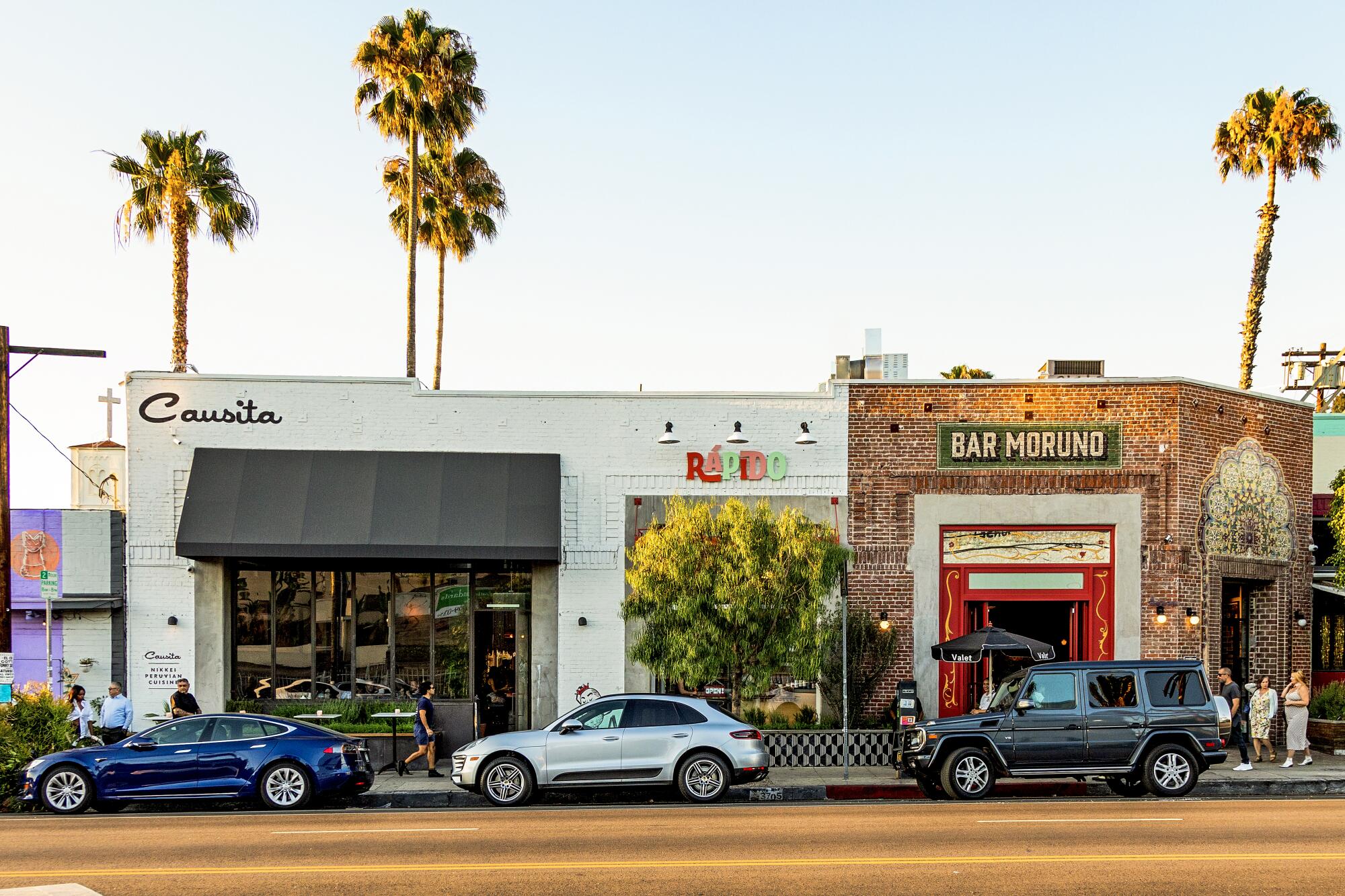 Three storefronts with cars parallel parked out front 