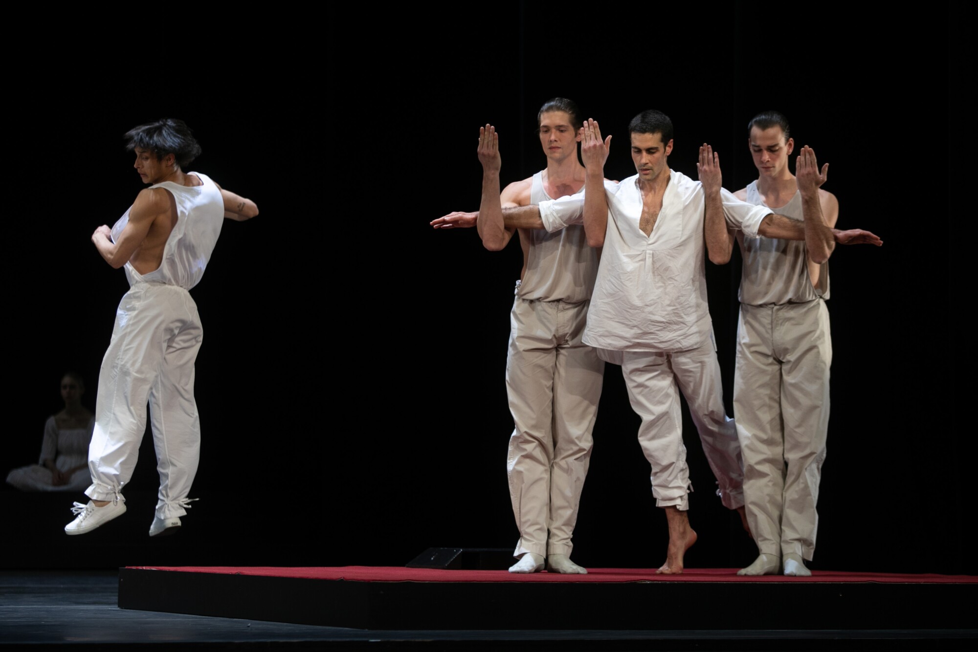 Two male dancers support a third, his arms perpendicular.
