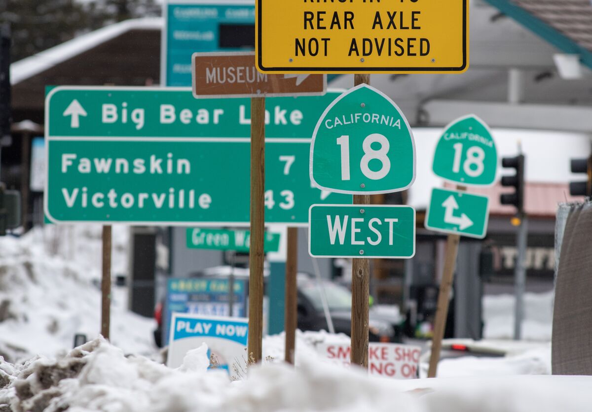 A cluster of street and highways signs standing in  snow.