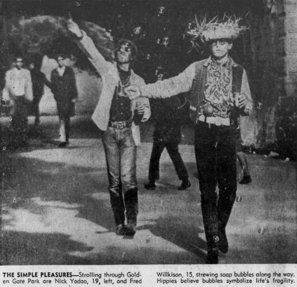 A clipping from a newspaper shows two men in sunglasses and necklaces walking on a sidewalk, waving bubble wands.