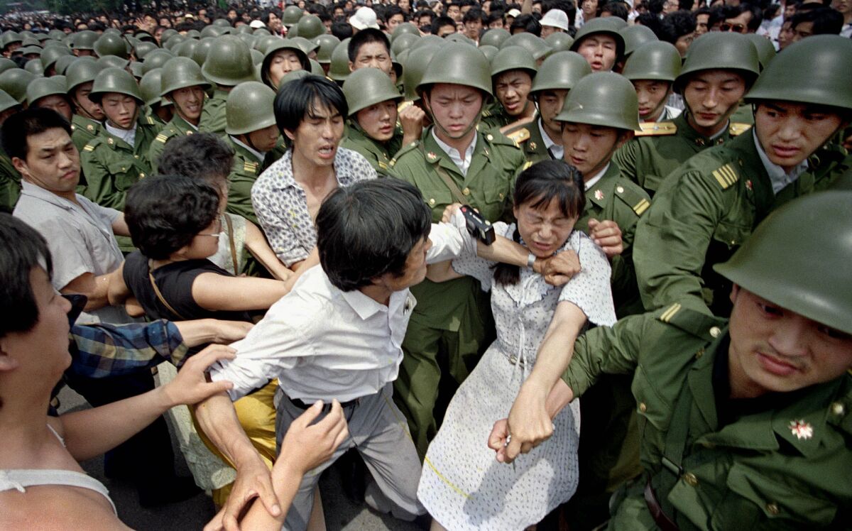 A woman is caught between civilians and soldiers, who were trying to remove her from an assembly near the Great Hall of the People in Beijing on June 3, 1989.