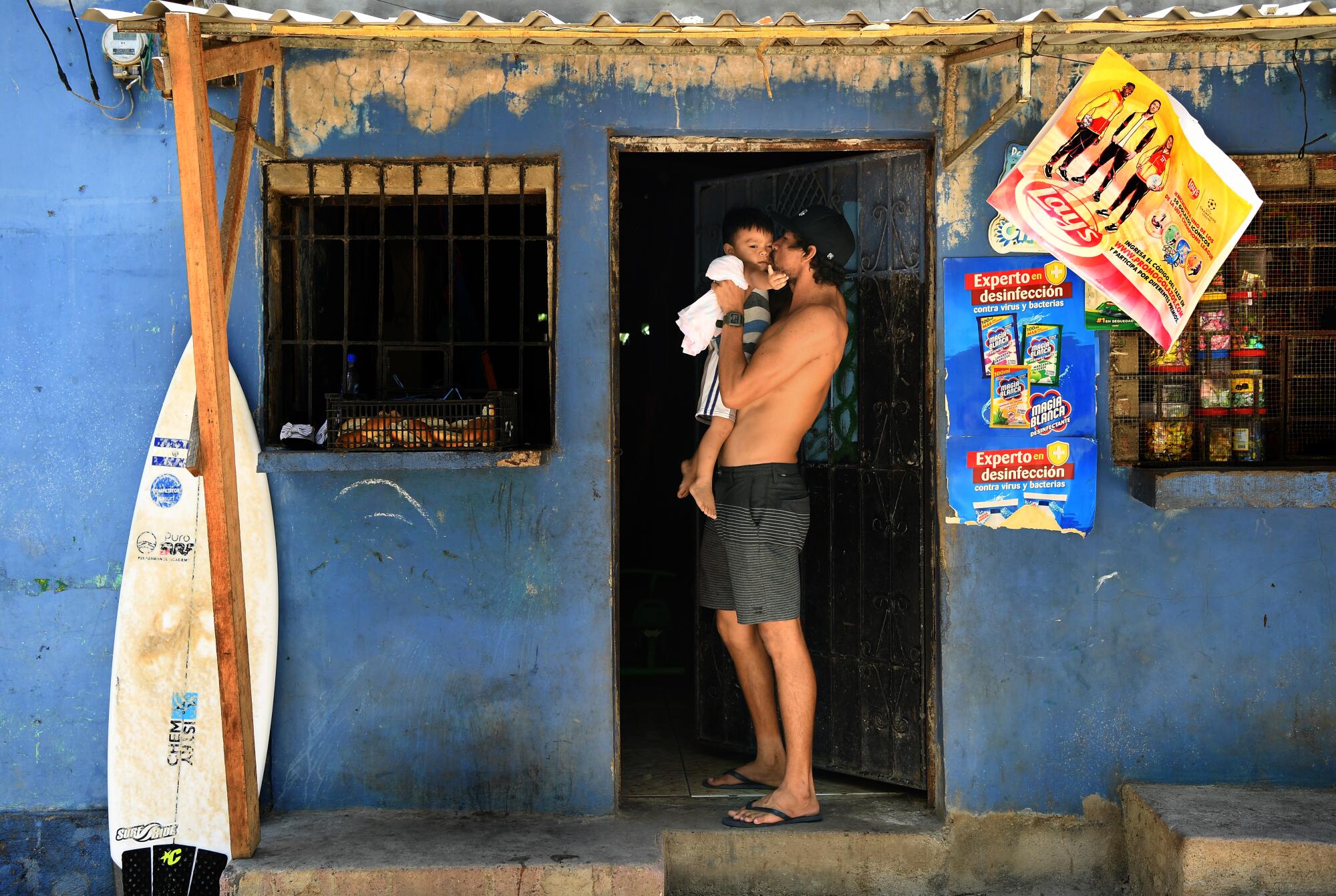  Surfer Bryan Perez holds his nephew outside his mother's store 