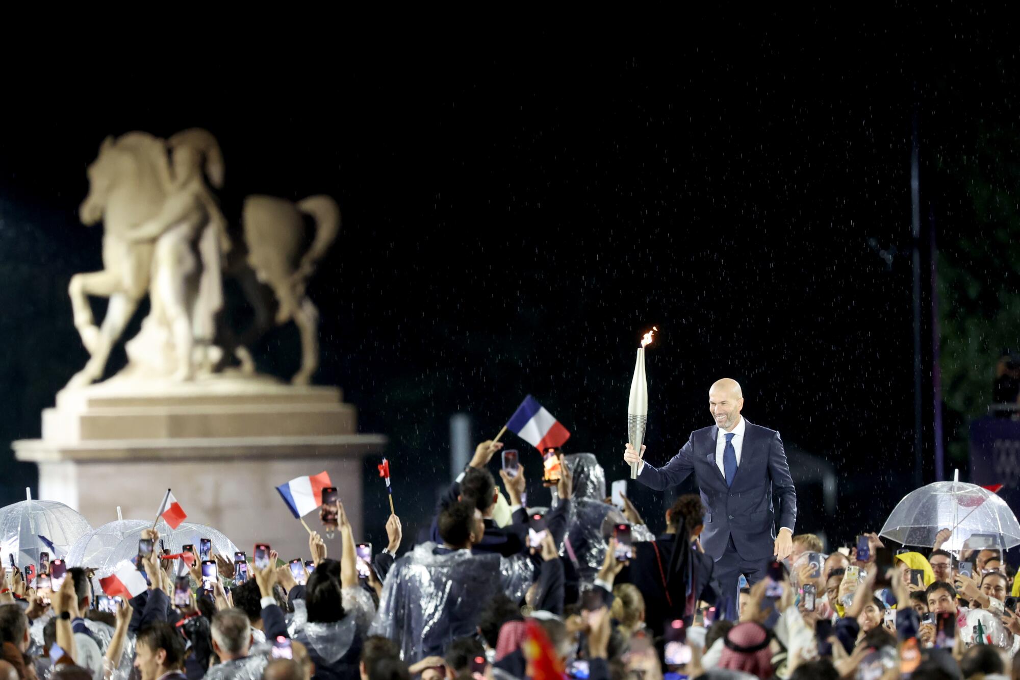 French soccer legend Zinedine Zidane carries the Olympic Torch during the opening ceremony.