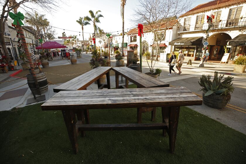 VENTURA, CA - DECEMBER 17: Few people walk past the empty fenced area containing tables but no chairs of Anacapa Brewing on East Main Street in downtown Ventura as Health officials in Ventura County say parties, indoor church services and youth sports events currently banned amid COVID-19 restrictions are continuing, hindering the county's ability to fight the spreading coronavirus. The county's intensive care unit capacity has dropped to 1%, and COVID-19 hospitalizations have broken records for 10 consecutive days. On Sunday, 181 COVID-19 patients were in the county's hospitals, 72% higher than the peak of the July surge. Ventura County on Thursday, Dec. 17, 2020 in Ventura, CA. (Al Seib / Los Angeles Times)