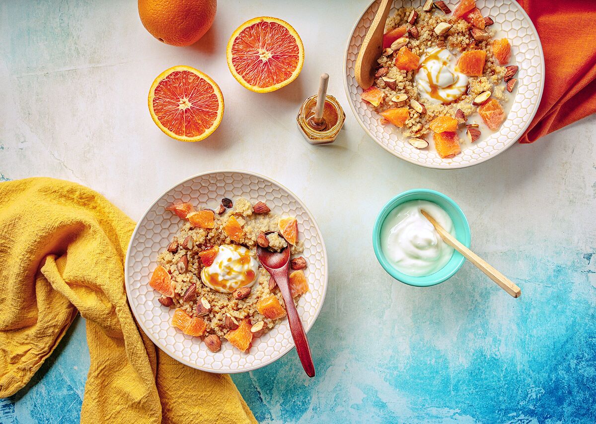Two bowls of cardamom quinoa porridge topped with Cara Cara oranges, almonds and yogurt.