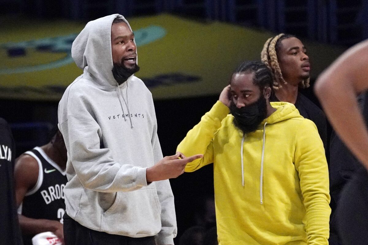 Brooklyn Nets forward Kevin Durant, left, and guard James Harden stand near the bench during the first half of a preseason NBA basketball game against the Los Angeles Lakers Sunday, Oct. 3, 2021, in Los Angeles. (AP Photo/Mark J. Terrill)