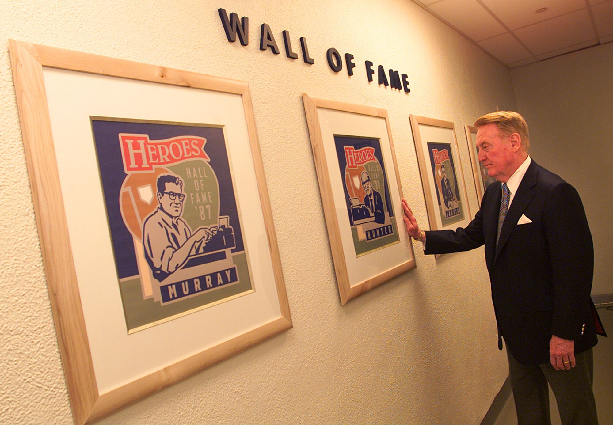 Dodgers announcer Vin Scully walks down the hall with the Wall of Fame in the press room.