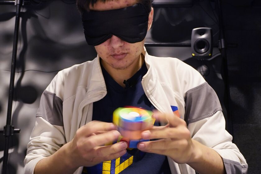 University of Michigan student Stanley Chapel solves a Rubik's Cube while blindfolded, Wednesday, Nov. 23, 2022, in Ann Arbor, Mich. Stanley is one of the world's foremost "speedcubers," a person capable of quickly solving a Rubik's Cube. He also is an accomplished violinist. Chapel says the two fields aren't as different as one might think. Chapel has certain inherent abilities -- he is capable of remembering and applying thousands of algorithms to solve a Rubik's Cube and performing one of Johann Sebastian Bach's violin sonatas from memory. (AP Photo/Carlos Osorio)