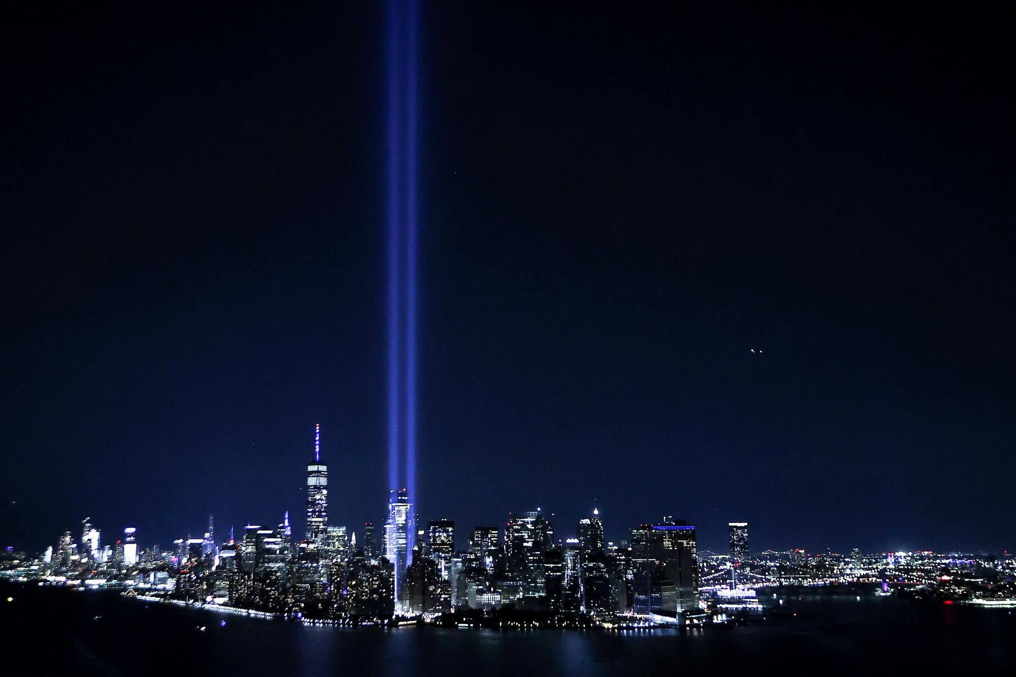 The Tribute in Light showing two columns of light reaching into the night sky shines up from the Manhattan skyline.