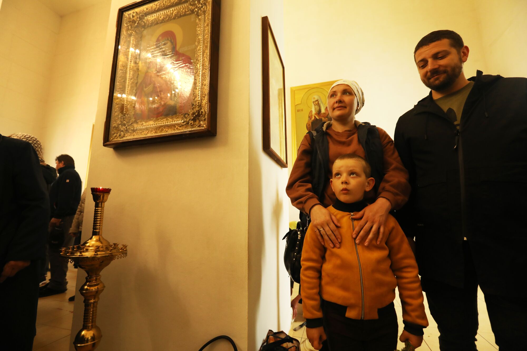 A woman and her husband stand in a church with their 5-year-old son.