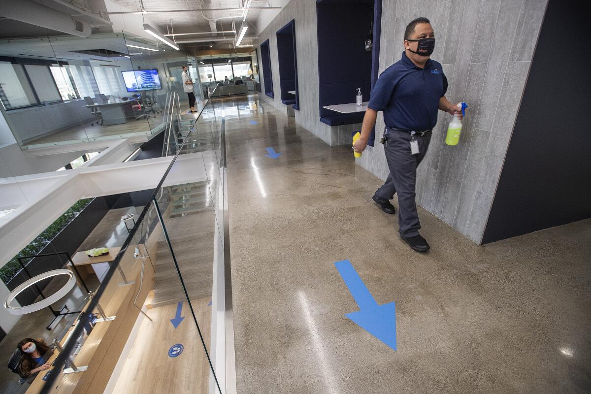 A man walks with disinfectant while cleaning a common area at Hudson Pacific Properties in Los Angeles.