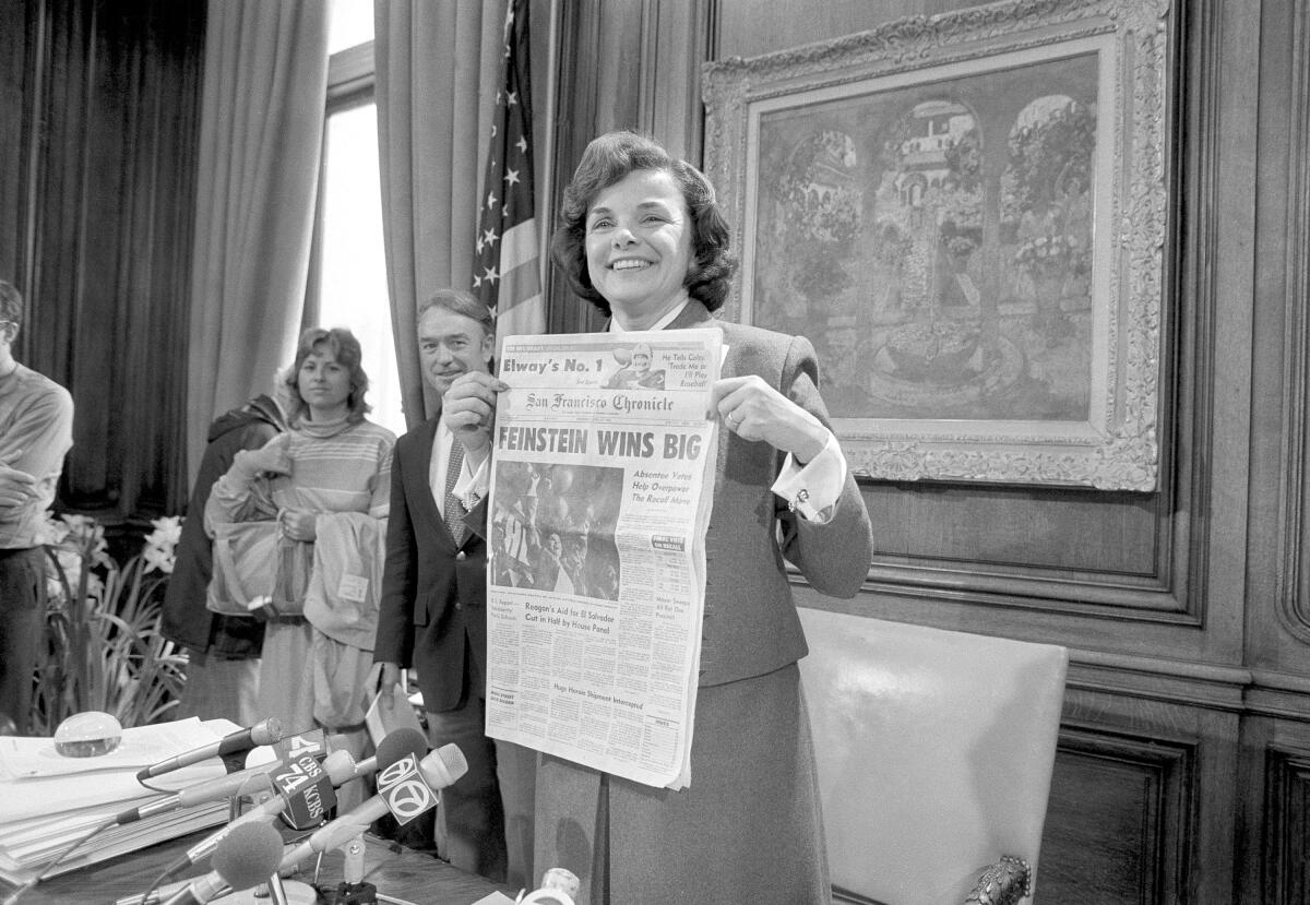 San Francisco Mayor Dianne Feinstein holds up a newspaper in her office after her sweeping victory in a recall election