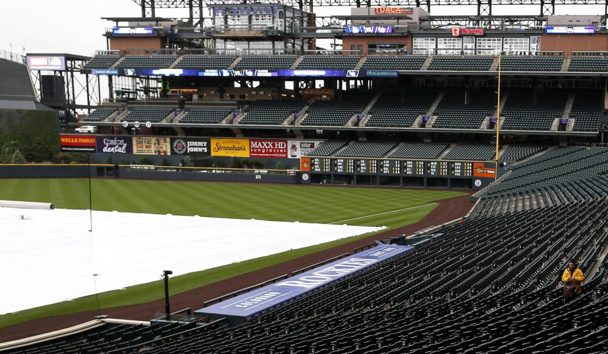 A lone guard moves through the empty stands at Coors Field on Saturday after the cancellation of the game between the Dodgers and Rockies.