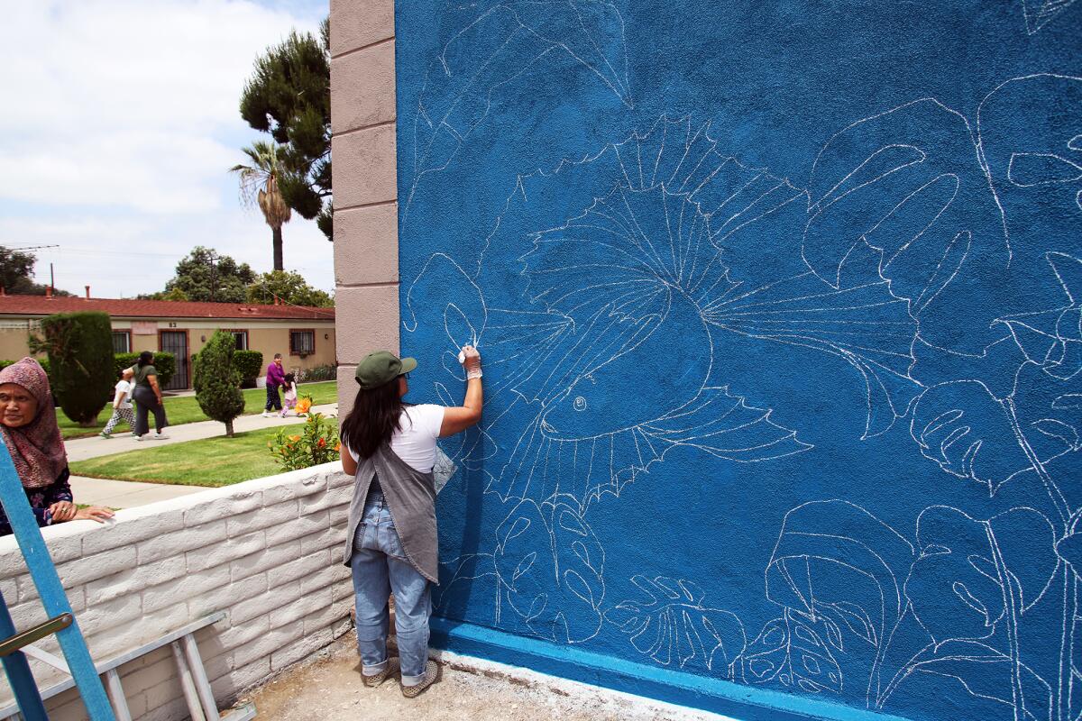 Sheryl Roth draws a mural she designed at the playground at Bishop Manor in Santa Ana.