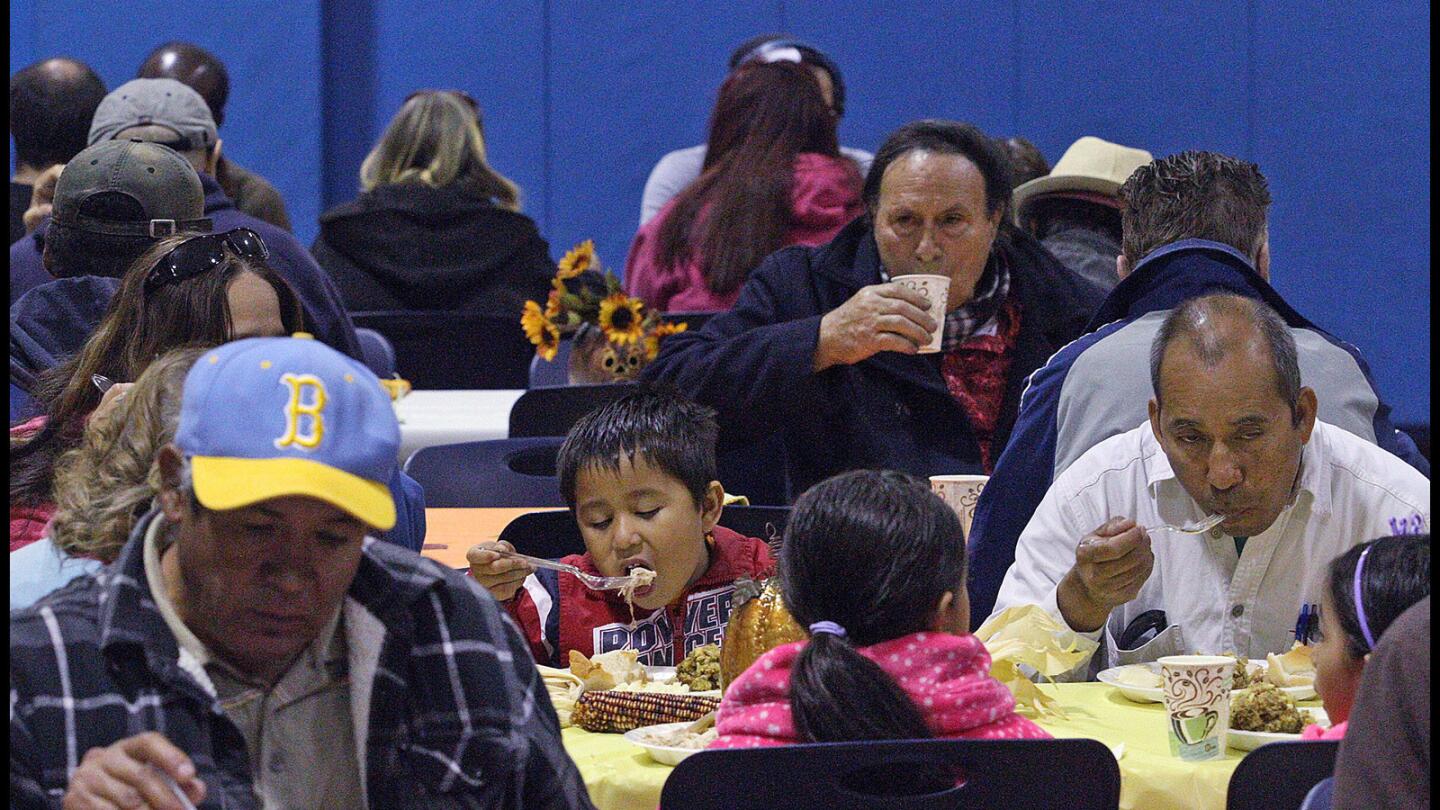 Charlie Toledo, 5, takes a big bite of turkey at the Salvation Army Glendale Corps and Community Center Thanksgiving dinner in Glendale on Thursday, November 26, 2015.