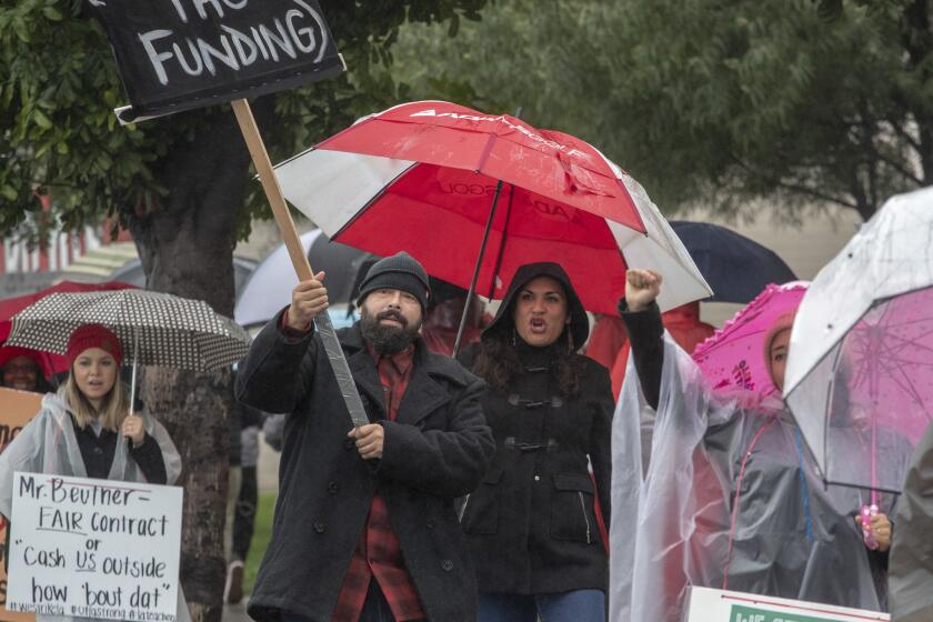 WILMINGTON, CALIF. -- WEDNESDAY, JANUARY 16, 2019: Banning High teacher Arnoldo Vargas, left, holds a sign while walking a picket line in front of Banning High School with his wife Maricela, right, in Wilmington, Calif., on Jan. 16, 2019. (Brian van der Brug / Los Angeles Times)