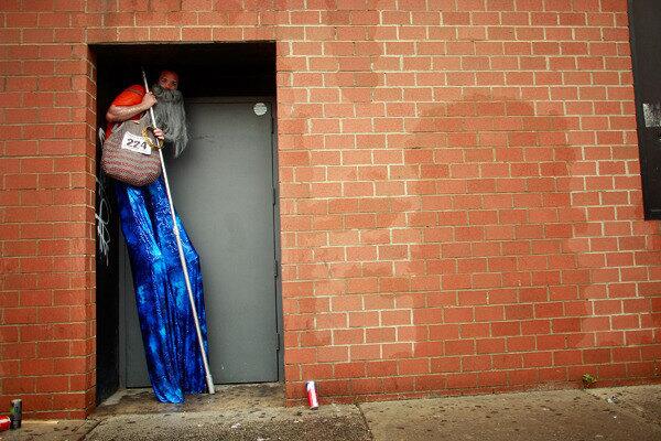 A stilt walker hides from the rain before the start of the 2009 Mermaid Parade at Coney Island.