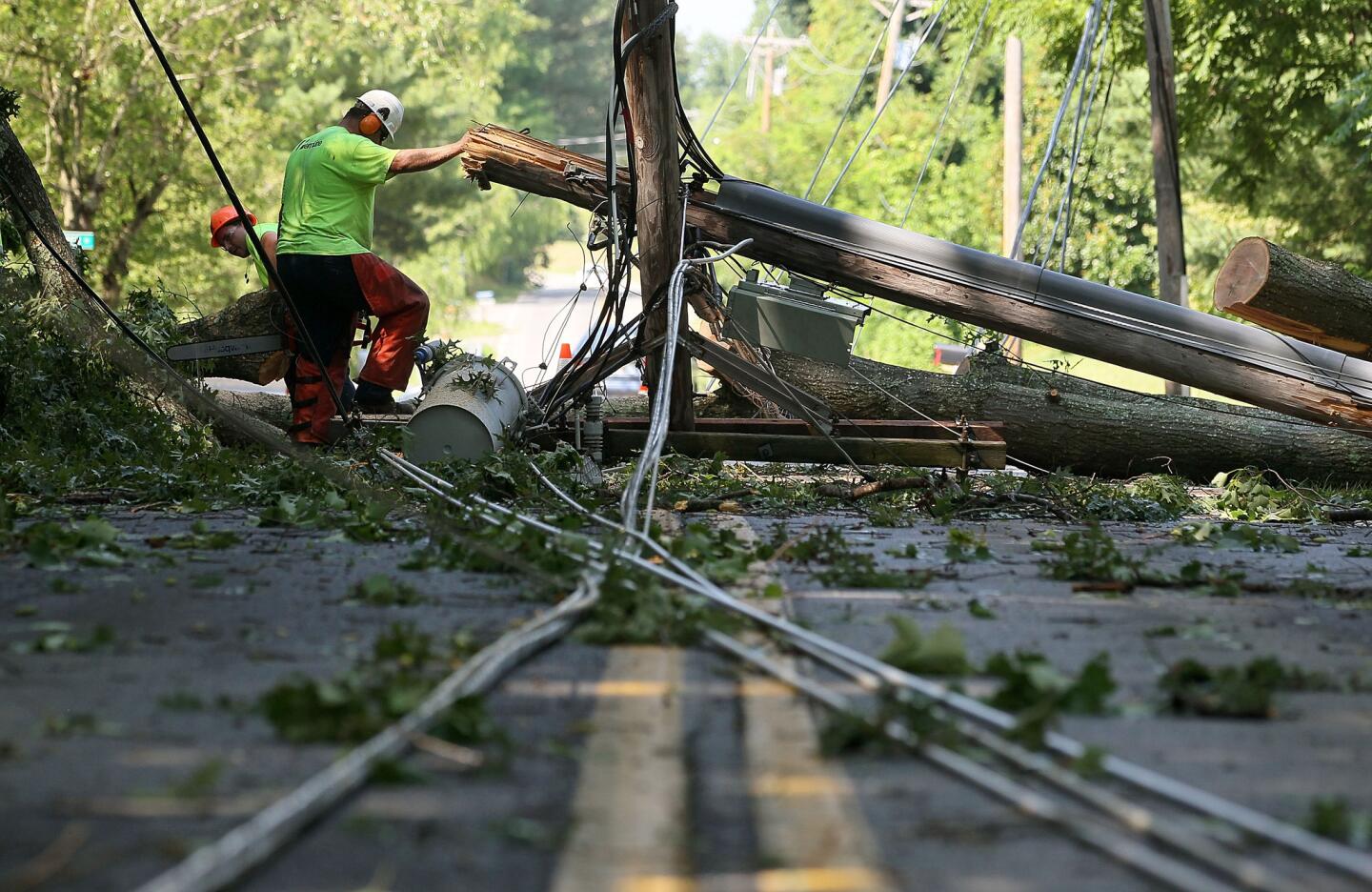 Workers cut up a fallen tree so that power lines can be repaired in Huntingtown, Md. More than a million homes across the Washington, D.C., area lost power after a severe thunderstorm.