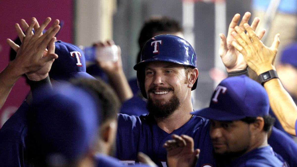 Rangers left fielder Josh Hamilton is congratulated by teammates in the dugout after scoring against the Angels in the fifth inning Friday night in Anaheim.