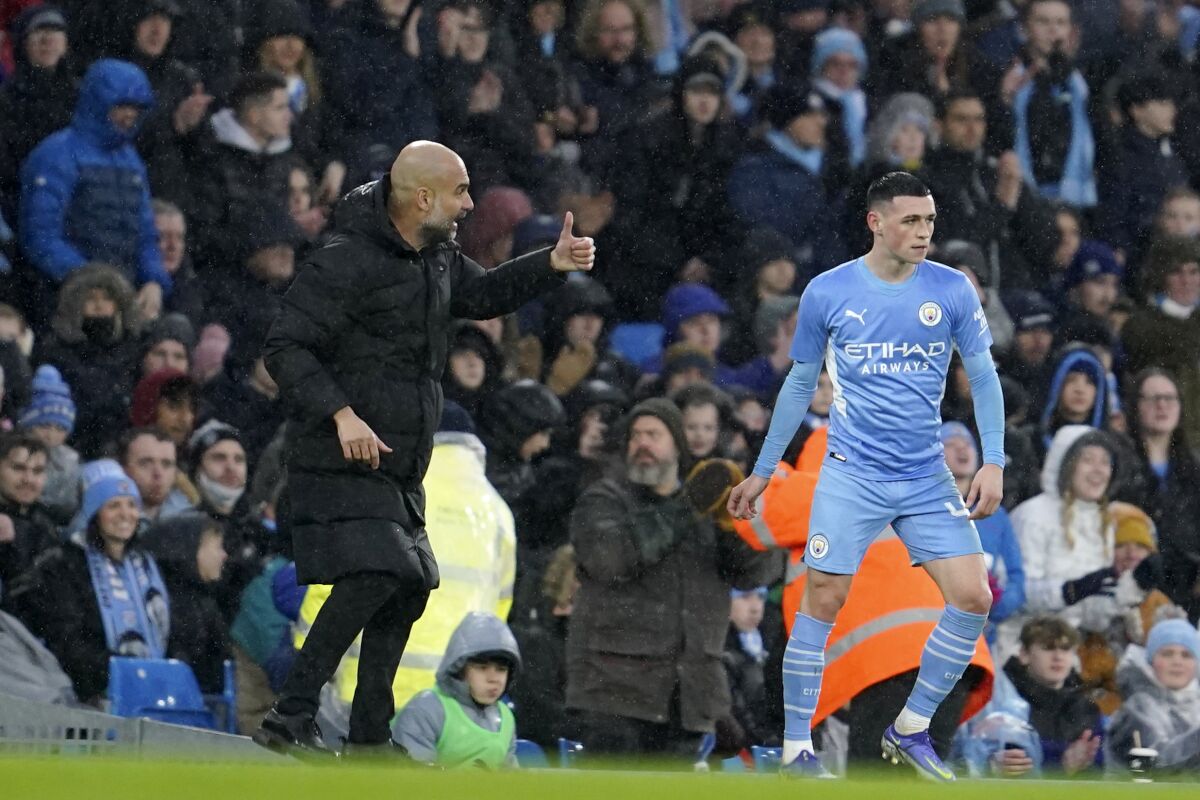 Manchester City's head coach Pep Guardiola gestures to Manchester City's Phil Foden during an English FA Cup fourth round soccer match between Manchester City and Fulham at the Etihad Stadium in Manchester, England, Saturday, Feb. 5, 2022. (AP Photo/Jon Super)