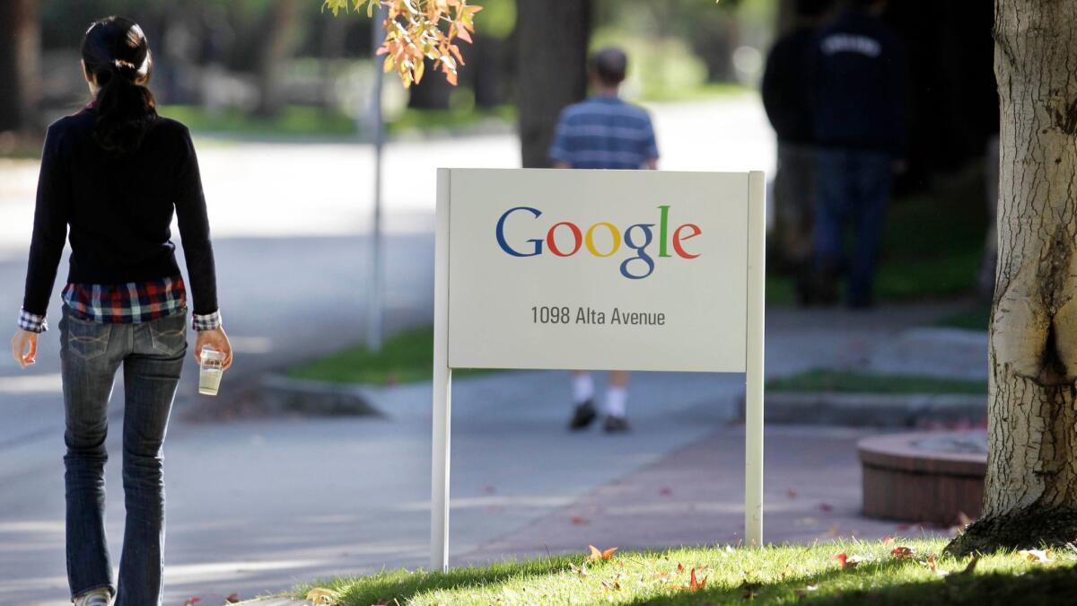 Google workers walk on the company's Mountain View, Calif. campus